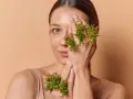 Kobieta z zielonymi ziołami na dłoniach, które zakrywają jej oko. Naturalne zioła na skórę dla pięknego wyglądu.