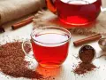 Czerwona herbata rooibos, znana ze swoich właściwości zdrowotnych, w szklanej filiżance, obok cynamonu i gwiazdki anyżu.