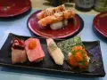 Różnorodne sushi na czarnym talerzu: kawałki mięsa, tuńczyka, kraba z wasabi i ikry. To wszystko, co potrzebne, by zrozumieć, co to są nukleotydy – budulec życia!