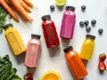 Kolorowe butelki z sokami, marchewki, szpinak i owoce – idealny zestaw na detox organizmu.