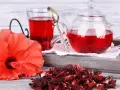 Czerwony napar z hibiskusa, świeży kwiat i suszone płatki. Choć hibiskus działa korzystnie, warto pamiętać o potencjalnym działaniu niepożądanym.