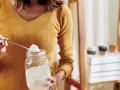 Kobieta nabiera łyżką sodę oczyszczoną do słoika. Czy soda oczyszczona jest zdrowa? To pytanie nurtuje wiele osób.