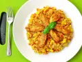 Pyszna kasza bulgur z kurczakiem, kukurydzą i marchewką, udekorowana listkiem bazylii. Obok leży widelec.