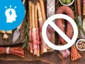 Unikaj wędlin, serów i pieczywa, jeśli chcesz stosować dietę przy migrenie. Ikona głowy z błyskawicą symbolizuje ból.
