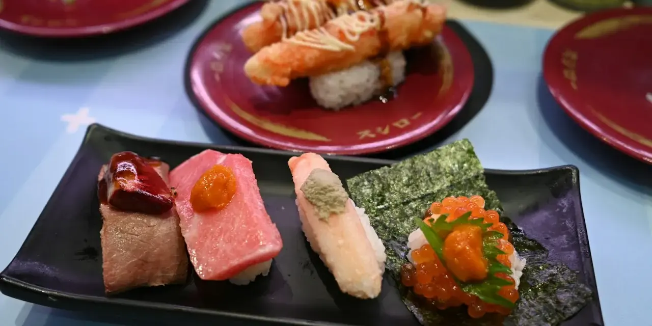 Różnorodne sushi na czarnym talerzu: kawałki mięsa, tuńczyka, kraba z wasabi i ikry. To wszystko, co potrzebne, by zrozumieć, co to są nukleotydy – budulec życia!