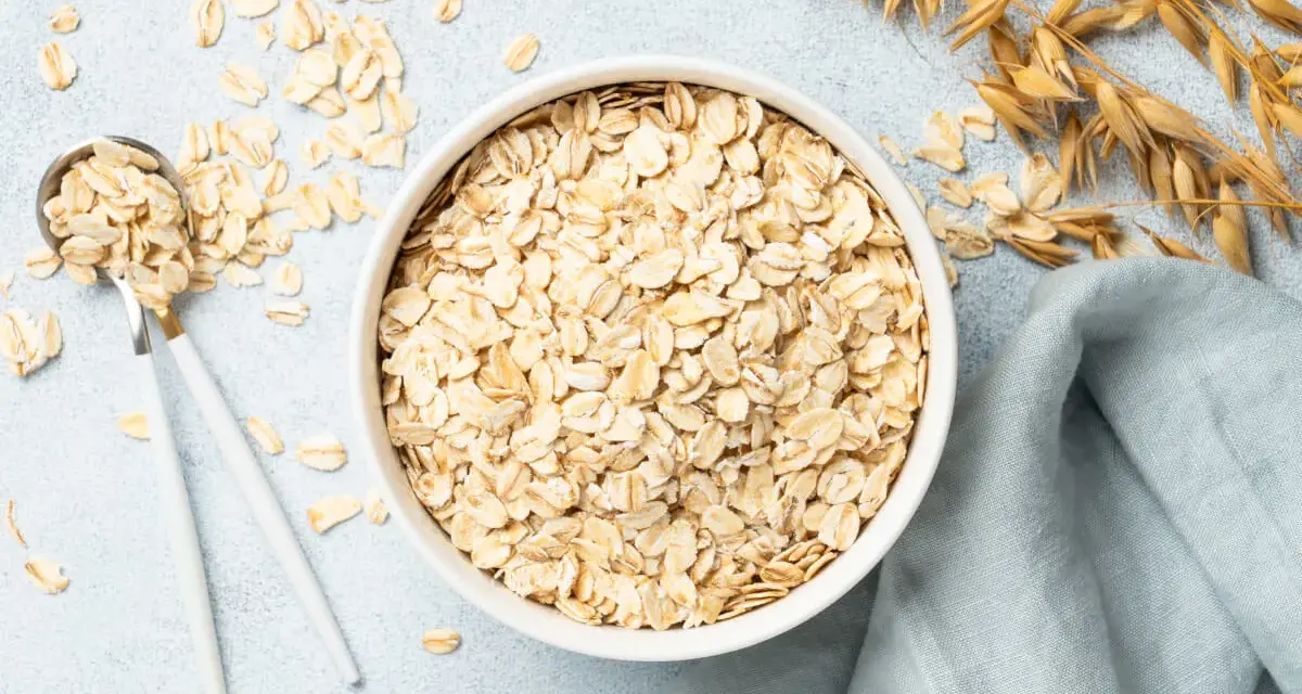 Misternie ułożone płatki owsiane w misce i na łyżce. Czy płatki owsiane mają gluten? Zależy od sposobu przetworzenia.