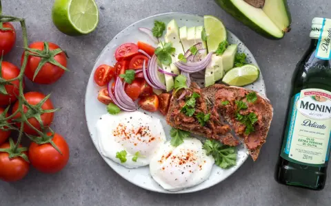 Śniadanie idealne na dietę 1500 kcal: jajka sadzone, tost z pastą, awokado, pomidorki, cebula i limonka.