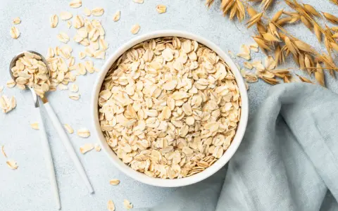 Misternie ułożone płatki owsiane w misce i na łyżce. Czy płatki owsiane mają gluten? Zależy od sposobu przetworzenia.