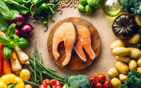 Dwa soczyste steki z łososia na desce, otoczone świeżymi warzywami i ziołami. Idealna dzienna dawka omega 3 dla zdrowia.
