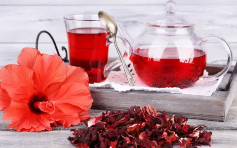 Czerwony napar z hibiskusa, świeży kwiat i suszone płatki. Choć hibiskus działa korzystnie, warto pamiętać o potencjalnym działaniu niepożądanym.