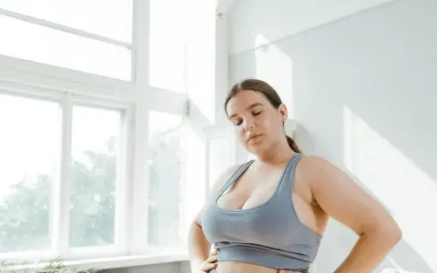Kobieta w sportowym topie zamyka oczy, zastanawiając się nad zdrowym odżywianiem. Dieta przy endometriozie może przynieść ulgę.