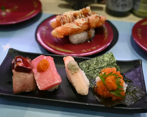Różnorodne sushi na czarnym talerzu: kawałki mięsa, tuńczyka, kraba z wasabi i ikry. To wszystko, co potrzebne, by zrozumieć, co to są nukleotydy – budulec życia!