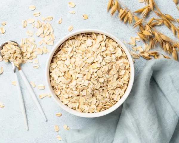 Misternie ułożone płatki owsiane w misce i na łyżce. Czy płatki owsiane mają gluten? Zależy od sposobu przetworzenia.
