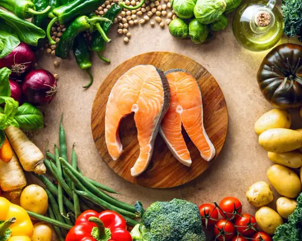 Dwa soczyste steki z łososia na desce, otoczone świeżymi warzywami i ziołami. Idealna dzienna dawka omega 3 dla zdrowia.