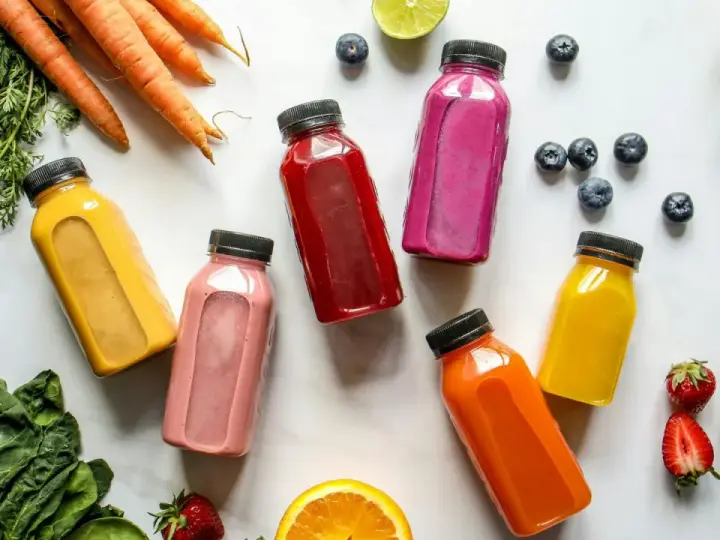 Kolorowe butelki z sokami, marchewki, szpinak i owoce – idealny zestaw na detox organizmu.