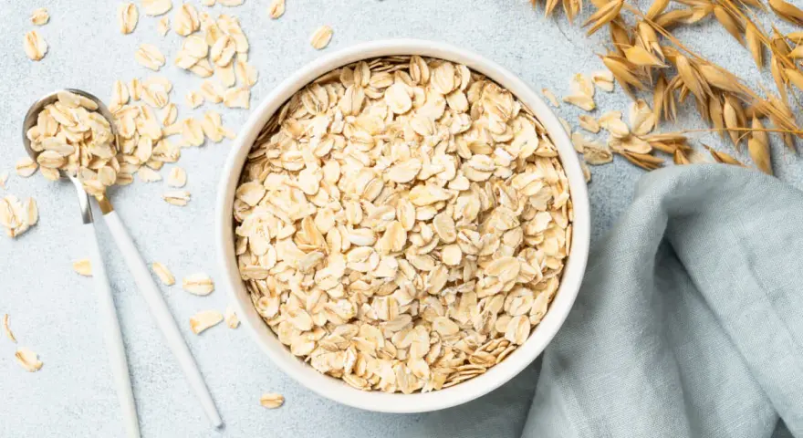 Misternie ułożone płatki owsiane w misce i na łyżce. Czy płatki owsiane mają gluten? Zależy od sposobu przetworzenia.