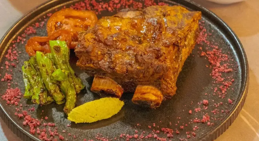 Soczysta żeberka wołowe w marynacie musztardowo miodowej, podane z pieczonymi pomidorami, zieloną papryką i puree.