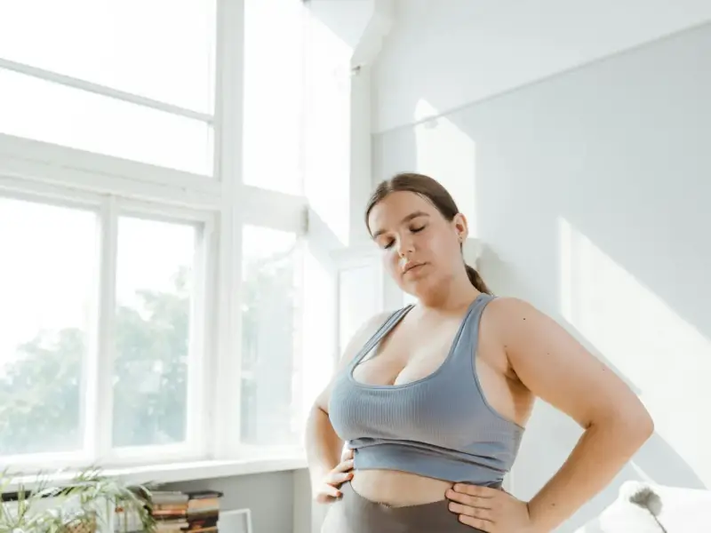 Kobieta w sportowym topie zamyka oczy, zastanawiając się nad zdrowym odżywianiem. Dieta przy endometriozie może przynieść ulgę.